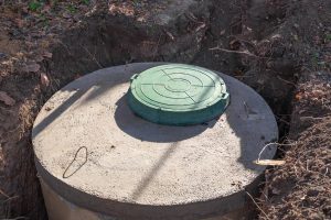 Concrete septic tank in ground with green hatch 
