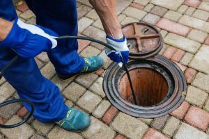Worker cleaning clogged drain with hydro jetting