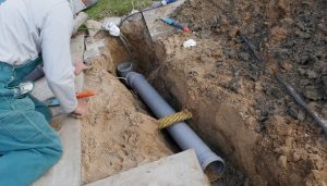 Modern PVC sewer pipe being installed in place of Orangeburg pipe