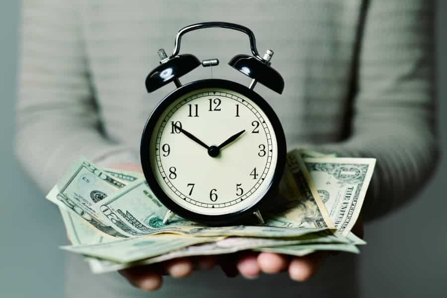 Person holding clock and money in hands