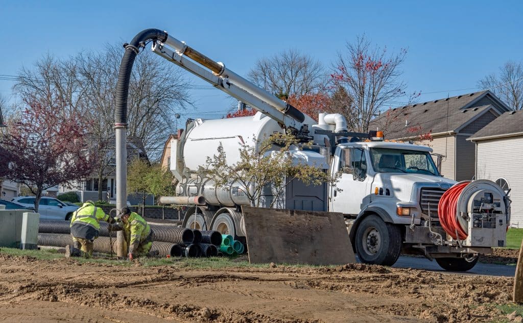 Hydro excavation vacuum truck creating hole in suburban neighborhood
