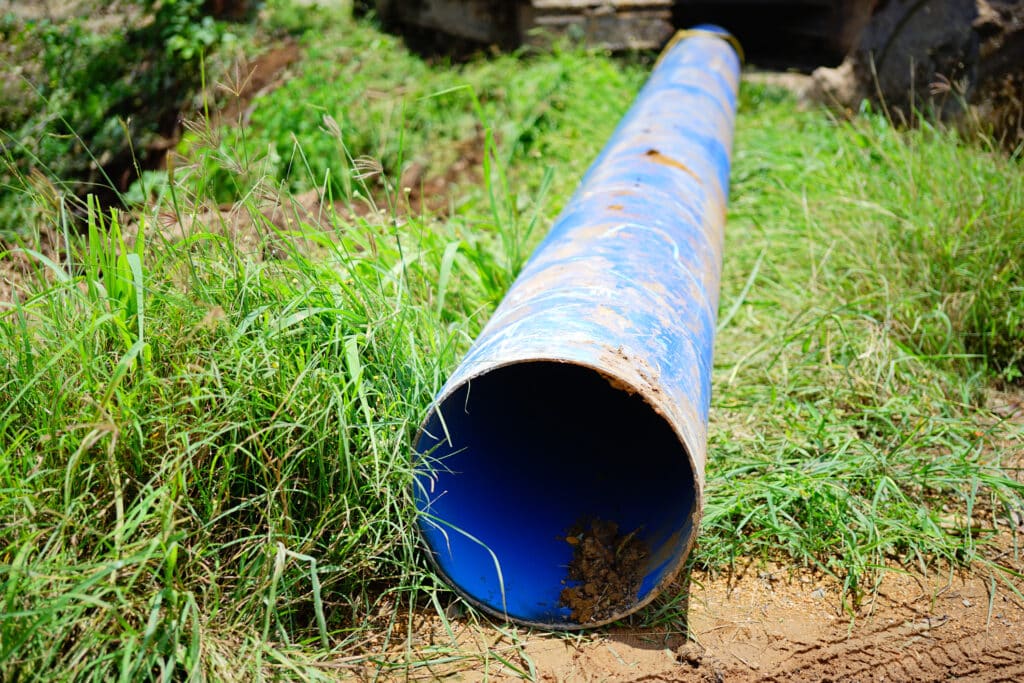 Dirty blue pipeline sitting on grass