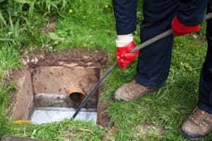 Drain being cleared by worker in navy overalls
