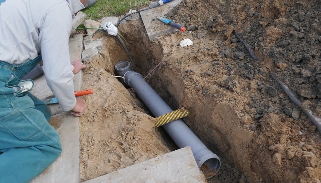 Worker laying and installing PVC sewer pipe
