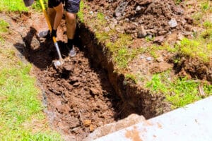 Worker digging trench with shovel for drainage pipe