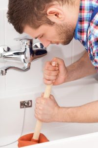 Homeowner attempting to unclog bathtub drain with plunger